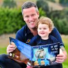 Dunedin firefighter Kris Kennett reads a copy of the book The Wolf Was Not Sleeping to his...