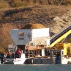 Smooth crossing ... Contractors pilot a barge laden with gravel and equipment across Lake Dunstan...