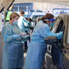 Two healthcare workers swab a man in his car. PHOTO: HUGH COLLINS