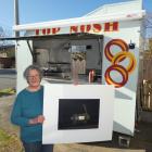 Jean Bonsor in her Top Nosh food trailer holds a signed copy of Grahame Sydney’s eponymous work....