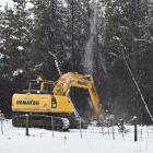 A digger works In the snow to dislodge hot spots amongst trees at the Pukaki fire on Tuesday...