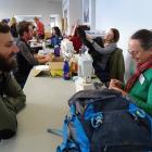 Dave Stewart, of Hawea Flat, watches Ros Goulding, from Deep Canyon, sew a tear in his backpack...