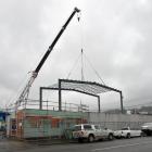 A crane supports a frame in place at a construction site in Ward St, Dunedin. Allied Pickfords...