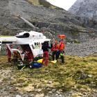 An injured climber is put into a helicopter after being lowered to a safe location and receiving...