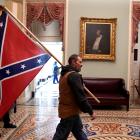 A supporter of President Donald Trump carries a Confederate battle flag on the second floor of...