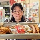 East Taieri Dairy and Takeaways owner Crystal Cao with a tray of food, typical of what she has...