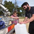 Karitane residents Lyell Owen (10) and dad Ben fill a container of water at the Karitane Hall...