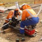 Workers join conductor cable by applying tonnes of clamping pressure on a sleeve to join the two...