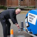 Roxburgh Area School principal Paul McDowall fills a bottle of water from a tank on school...