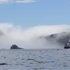 The Antipodes Islands emerge from a sea fog and The Spirit of Enderby  anchored in its waters.