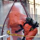 Two firefighters in hazmat suits are hosed down in the aftermath of a chemical spill at the PBT...