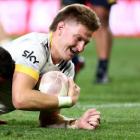 Jordie Barrett of the Hurricanes dives over to score a try while being tackled by Highlander...