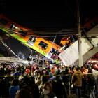 Rescuers work at a site where an overpass for a metro partially collapsed with train cars on it...