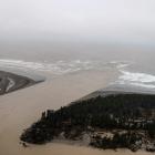 Sediment-laden floodwater pours out of the mouth of the Waimakariri River at Pines Beach, north...