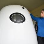 Jan Smith stands next to the personal hyperbaric chamber her husband used as therapy for motor...