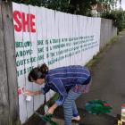 Iona Winter puts the finishing touches on her poem ‘‘Her’’ on a Port Chalmers fence. PHOTO: SUPPLIED