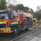 Fire and Emergency New Zealand firefighters mop up after a house fire in Warrington. PHOTO: LINDA...