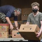 Volunteer Bob Donaldson (left) and Deloitte intern Finley Mahoney (20) move donated goods into...