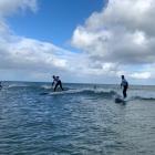 Farmers ride the crest of a wave at a Surfing for Farmers event at Kaka Point this summer.PC...