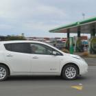 An electric vehicle passes a petrol station. PHOTO: GREGOR RICHARDSON