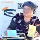 Street poet Angelina Stanton holds up her poem titled To The Readers written in the Octagon...