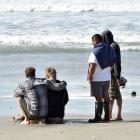 People comfort each other at a beach at Aramoana on Saturday, where surfer James Civil died....
