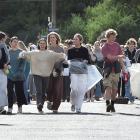 Students carrying bags and brooms arrive in Castle St yesterday during the annual North Dunedin...