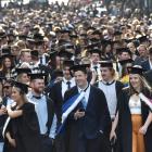 Several hundred University of Otago graduands stream along George St, Dunedin, in the university...