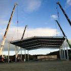 Four cranes lift a section of the roof of Road Metals’ new office and workshop development on...