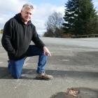 Lawrence resident Mark Robertson points to a water leak at the corner of Peel St and Ross Pl, one...