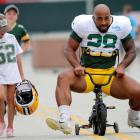 A young fan watches as Green Bay Packers running back AJ Dillon tries his best to ride her bike...