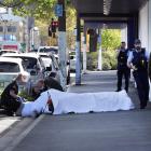 Ambulance officers with the injured man outside Rebel Sport, Crawford St, Dunedin. Photo by...