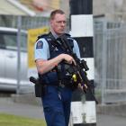 An armed police officer stands guard at a cordon at the intersection of Panmure Ave and Riselaw...