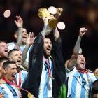 Messi holds the World Cup aloft amid jubilant celebrations from his Argentina teammates. Photo:...