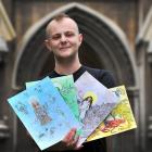 Dunedin entrepreneur Charlie O’Mannin holds the original illustrations created by Dunedin artists...