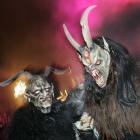 Two men dressed as Krampus, a devil-like figure and companion of St Nicholas, walk up the street...