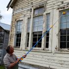 Taieri Historical Society committee member Pete Thomson cleans the windows of the former Outram...