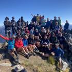 Standing on Corner Peak summit, 35 people join Glen Thurston (centre back, yellow shirt) for his...