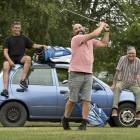 Sherman Weatherall tests his golf swing in front of his Toyota Scarlet, which he has put up for a...