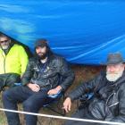 Taking shelter from the rain are (from left) Dennis Leveridge, Hamish Bauer and Brian ‘‘Cowboy’’...