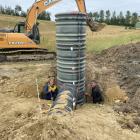 West Otago farmer Al Body (right) and his son Jack (15) compact soil around a detainment bund...