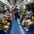 Passengers are wearing face masks as a staff member walks past them on the Beijing subway. Photo:...