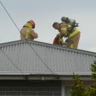 Balclutha firefighters wearing breathing apparatus prepare to damp down a roof fire on the town's...