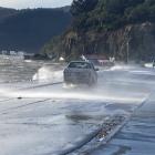 Waves from Otago Harbour are blown across the Portobello Road causeway. Photo: Stephen Jaquiery