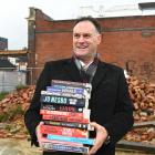 Dunedin Mayor Jules Radich holds a stack of books at the Wolfenden and Russell site in King...