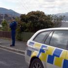 A scene guard stands outside a house in Columba Ave, Calton Hill, Dunedin, yesterday, where...