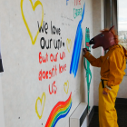A protester against staffing cuts at the University of Otago paints messages on a wall of a...
