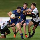 Otago midfield back Jake Te Hiwi fights off North Harbour defenders as he bursts upfield in his...