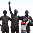 A fan places a scarf around the neck of a likeness of Manchester United and England footballing...