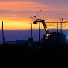 Contractors trim the tops off and remove poles from Holmes Wharf in Oamaru early on Friday...